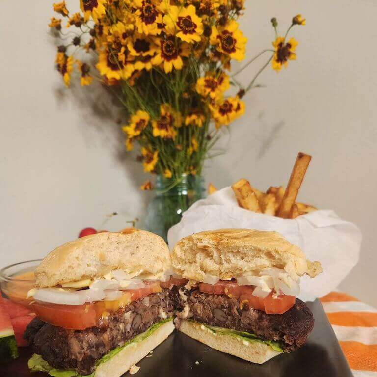 A black bean burger in a bun with vegetables cut into a cross section.