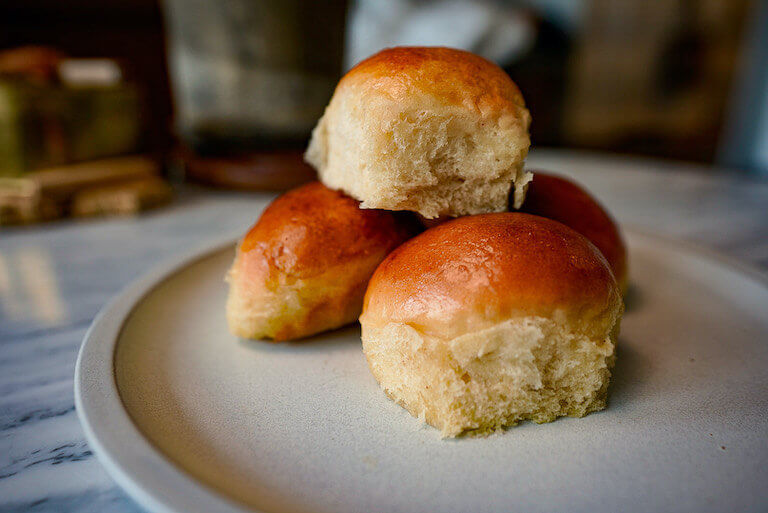 A plate of three golden brown bread rolls.