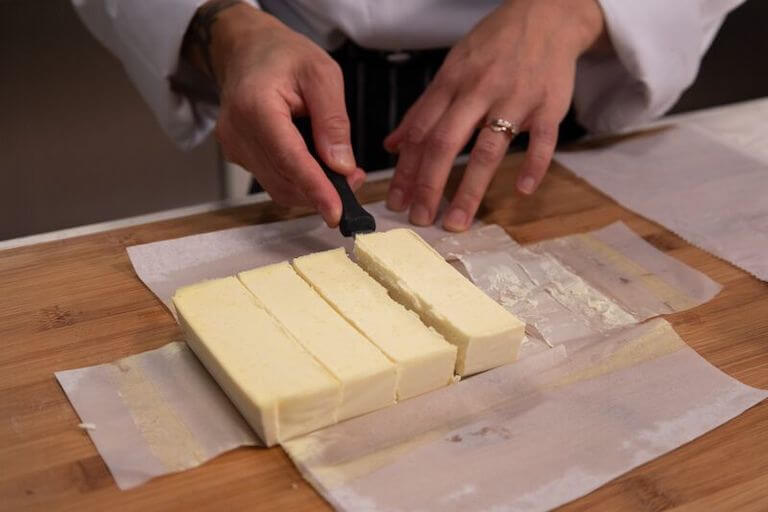 Chef slicing vegan butter into equal sections.