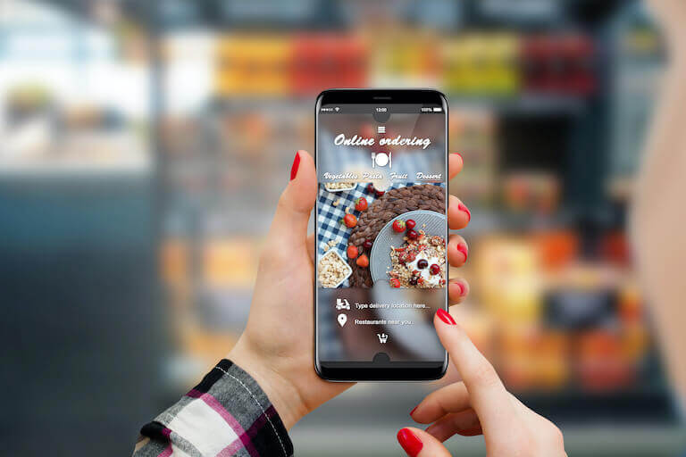 Close up of hands with red nails ordering food on their phone