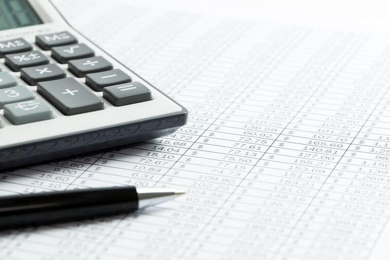 Closeup of a calculator and a pen sitting on a financial report.