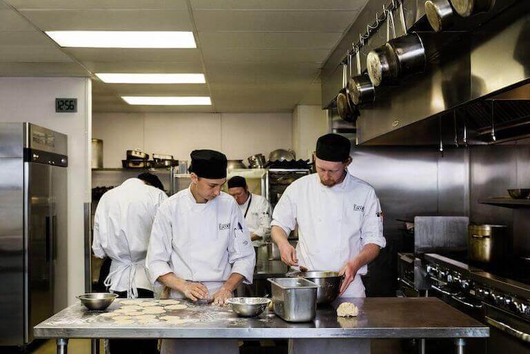 Escoffier student kneading dough flour in kitchen