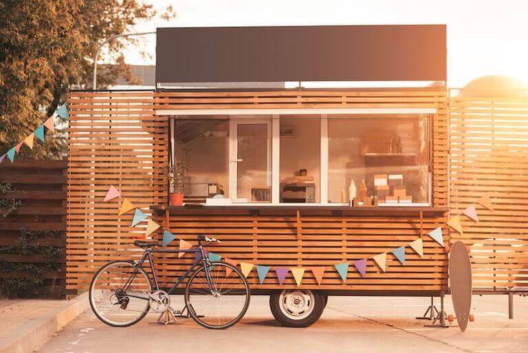 A food truck with a bicycle leaning against it.