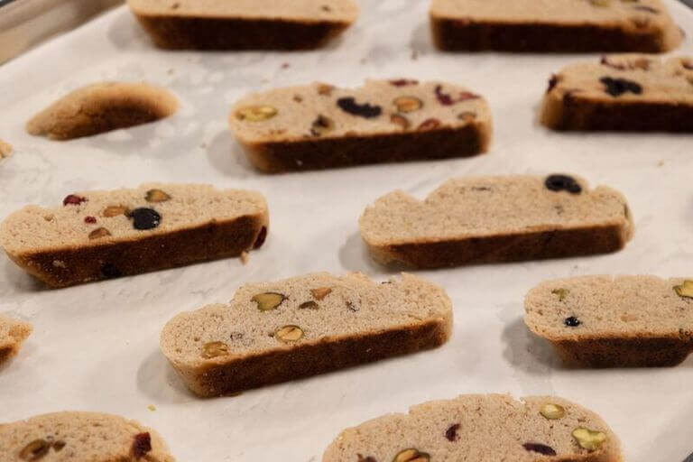 Pieces of biscotti are laid out on a parchment paper-lined baking sheet.