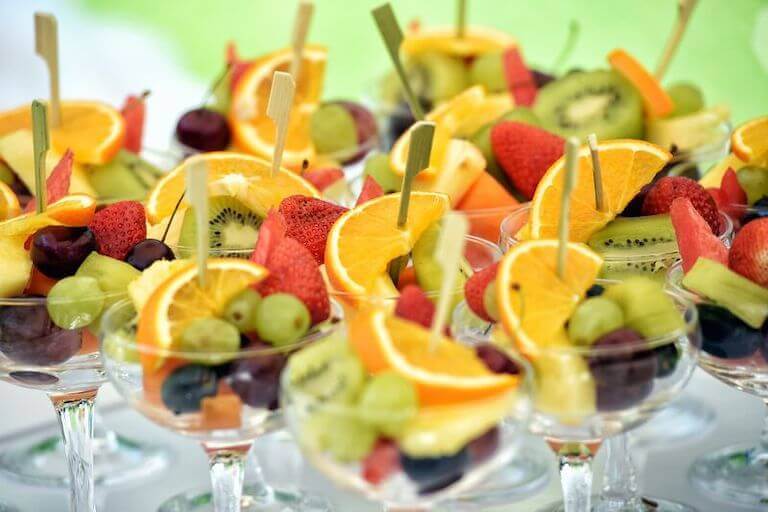 Fruit cocktails in elegant glasses with strawberries, oranges, and grapes.