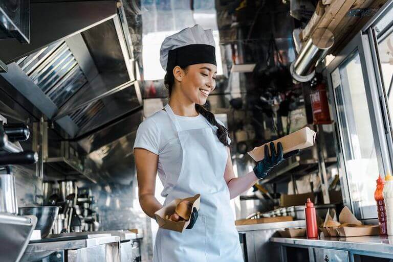 Smiling chef working in food truck kitchen serving customers through service window