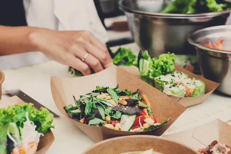Close-up of fresh salads being prepared in a fast-casual restaurant kitchen.