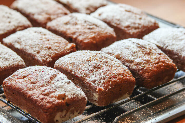 Several rows of fresh-baked bread loaves sit on a cooling rack.