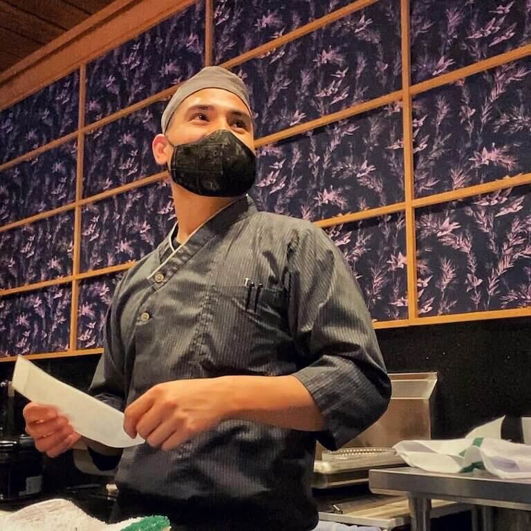 Osaka restaurant employee in dark uniform wearing a mask