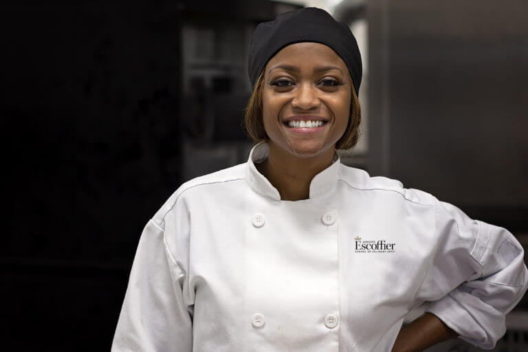Tiffany Moore, Auguste Escoffier School of Culinary Arts graduate, smiling at camera in professional headshot with Escoffier logo.