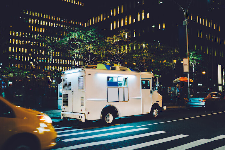 White food truck parked on city street near buildings