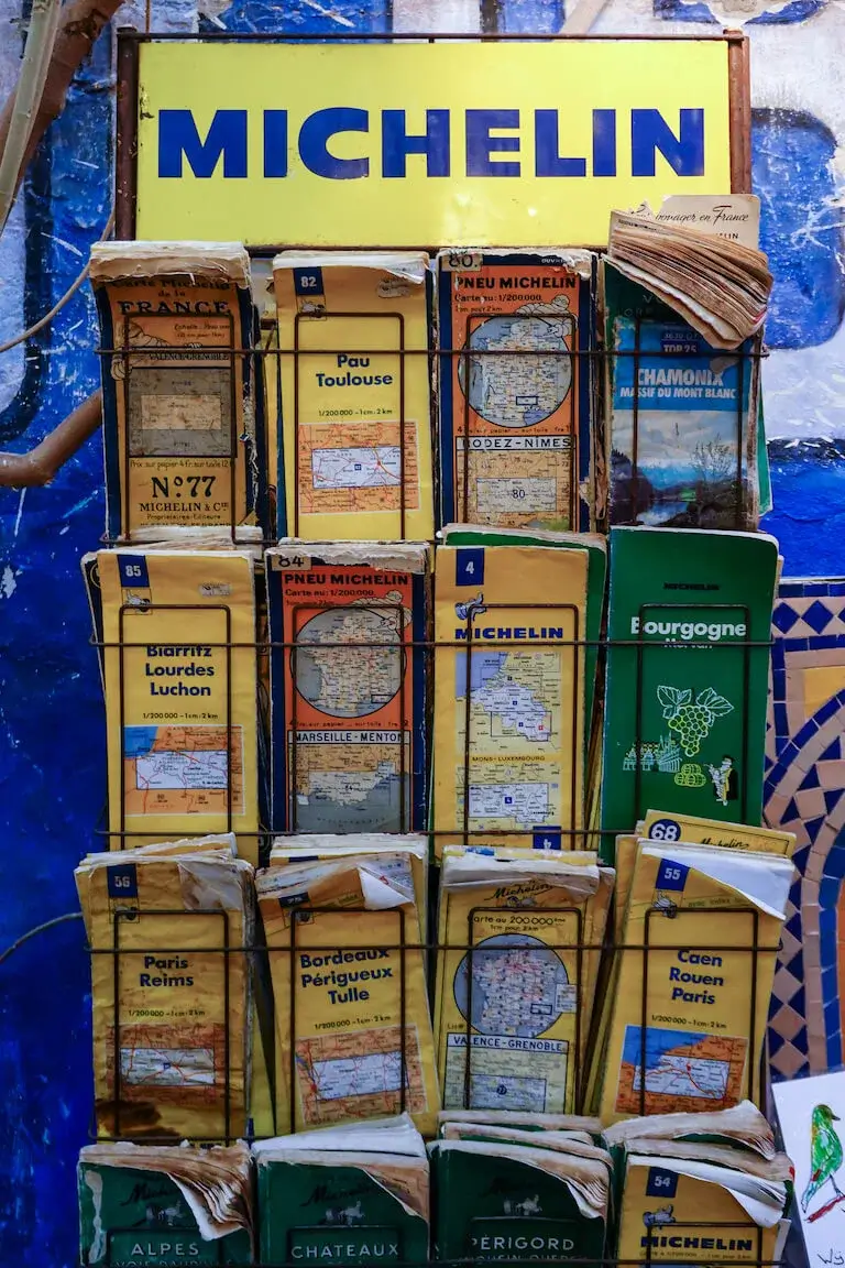 A collection of old Michelin travel guides and maps in a rack.