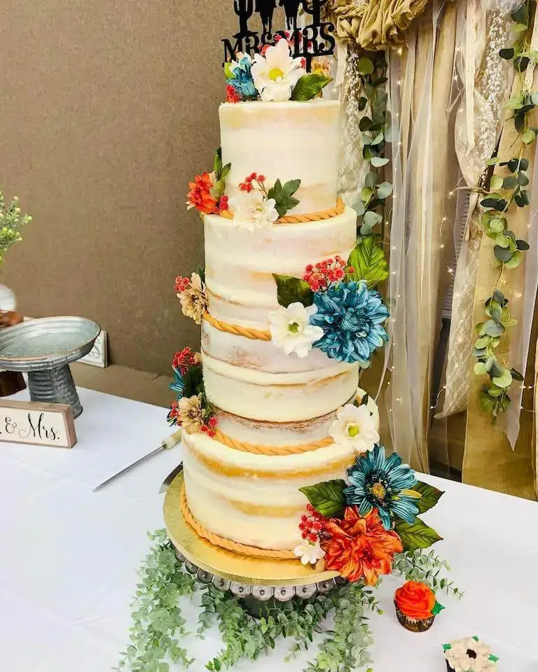 A multi-tiered wedding cake stands tall on a banquet table. It features floral accents and piping.