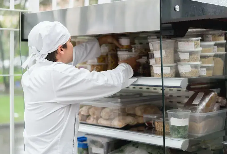Chef arranging labeled containers in a refrigerator.