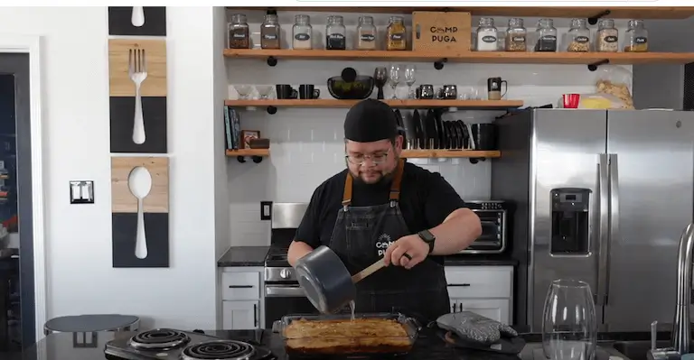 Chef Chris Puga pouring simple syrup on top of a glass dish with baked phyllo bread.