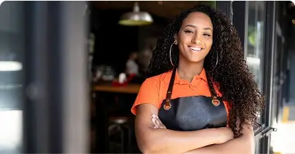 Confident restaurant chef in an apron smiling at the entrance of a cafe