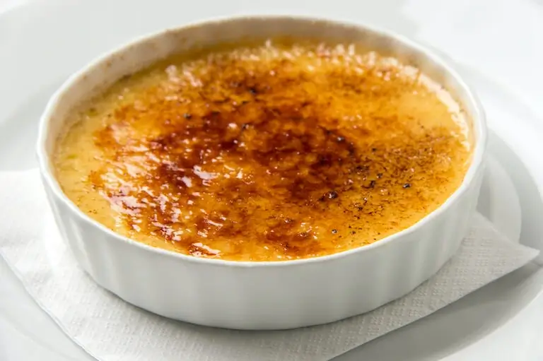Crème brûlée with caramelized sugar crust in a white ramekin.