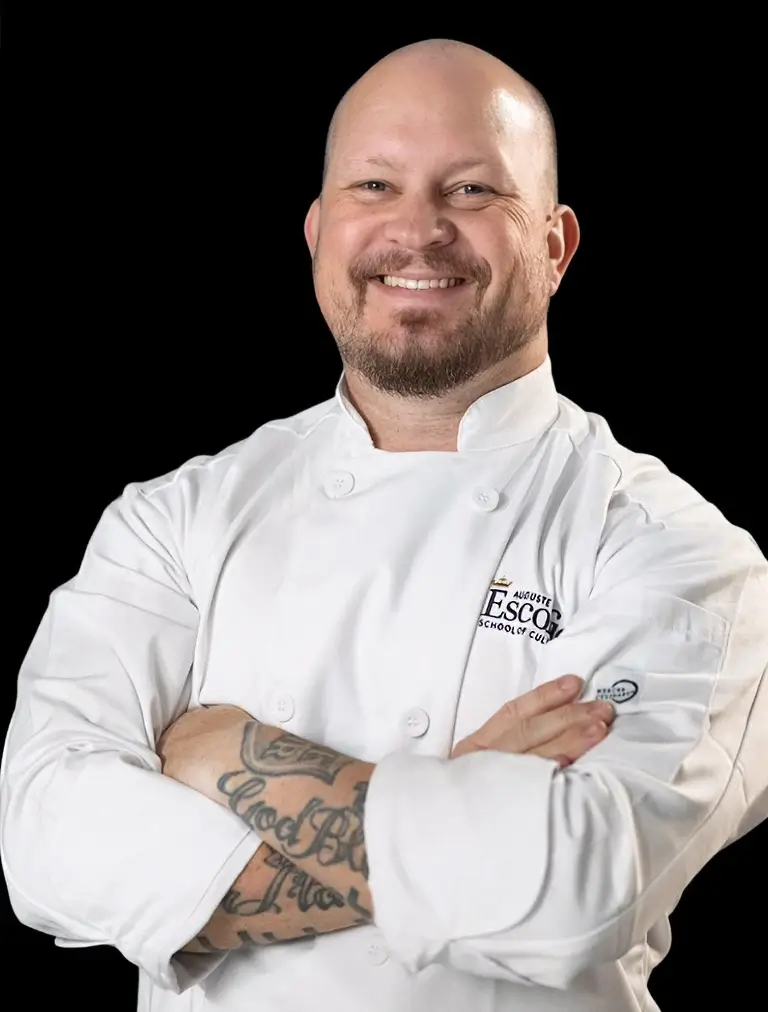 Portrait of a smiling Chef Instructor in chef whites in a teaching kitchen.